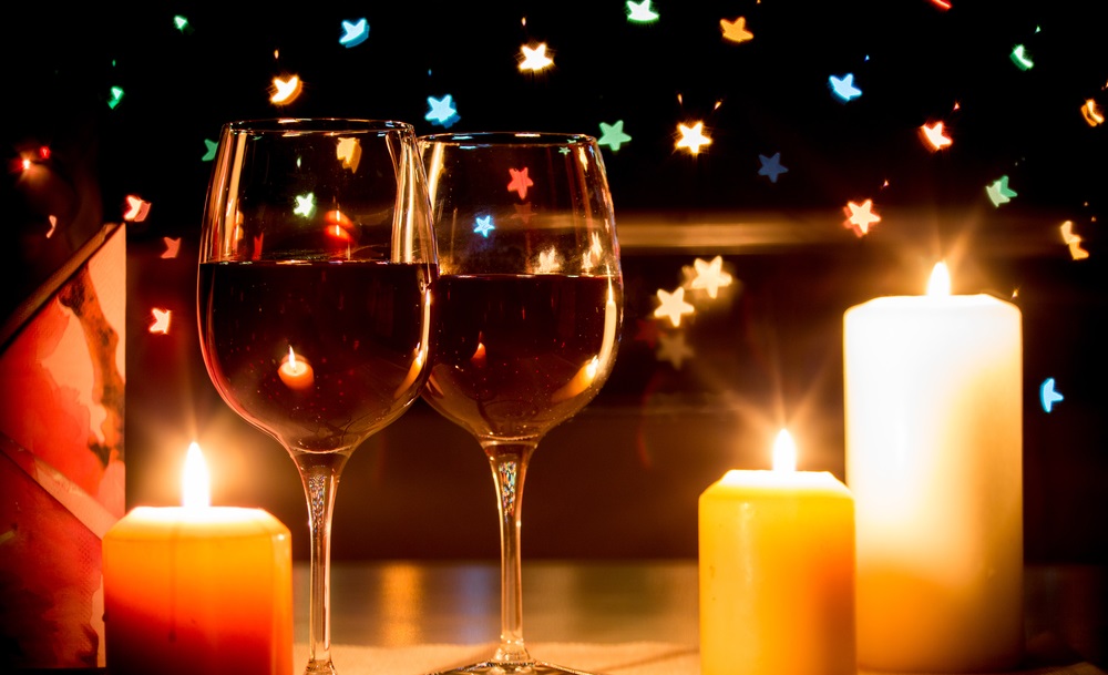 wine glasses on table next to lit candles